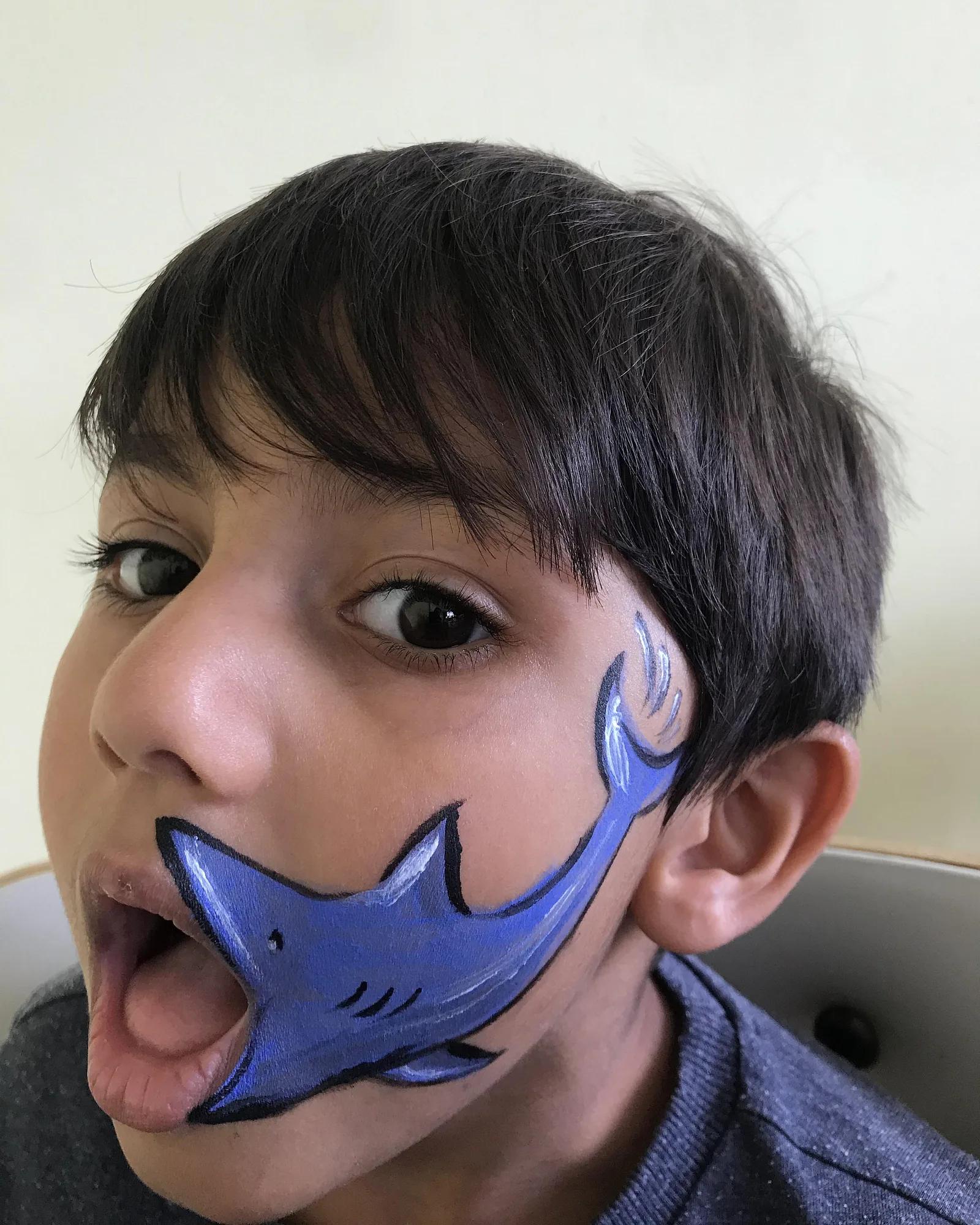 Piya face-painting a shark design on a child