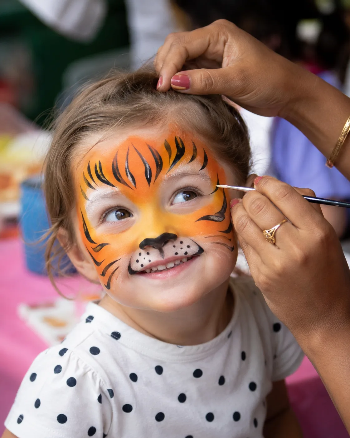 Piya face-painting a tiger design on a child